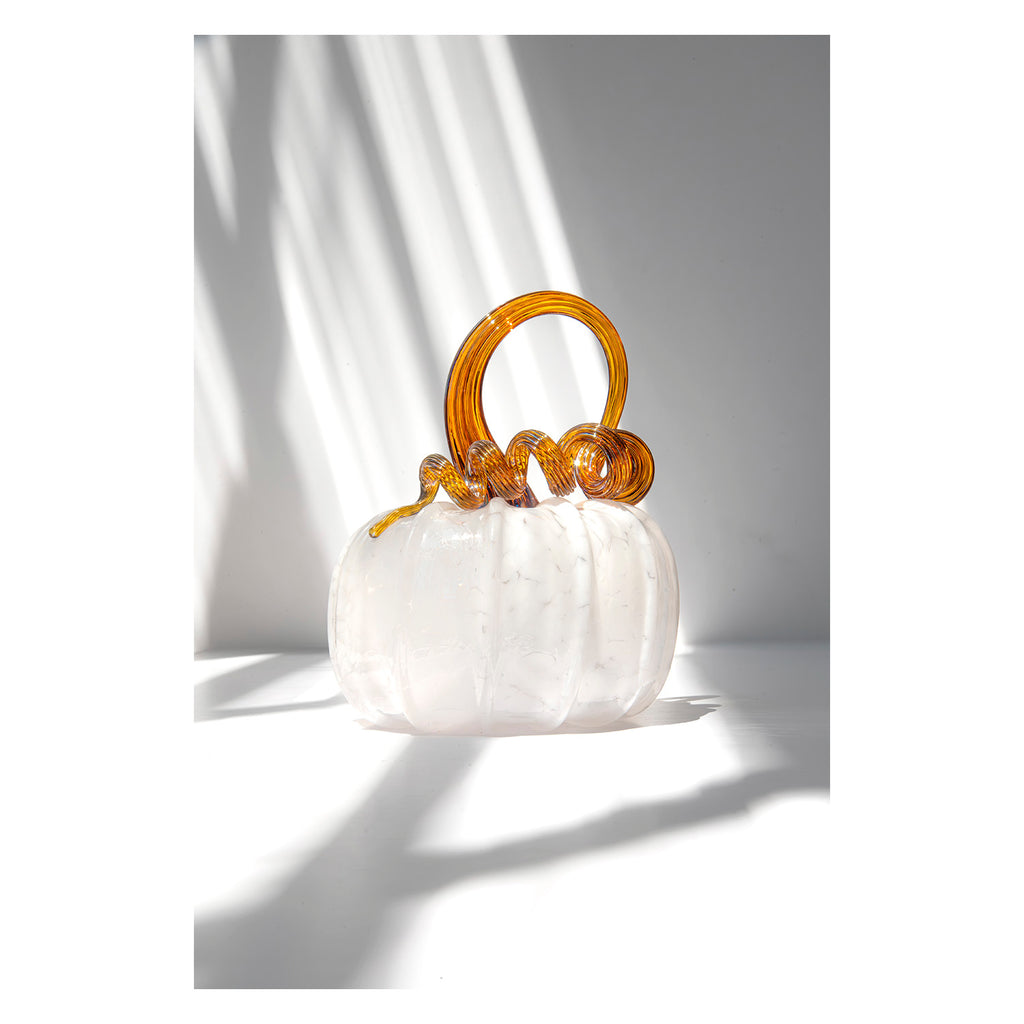 White glass pumpkin with gold stem on a white background